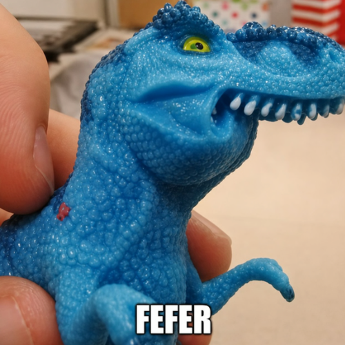 The FEFER meme: a sparkly blue rubber toy T-rex held between two fingers